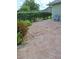 A partially shaded back patio featuring decorative concrete stones is accented with bordering greenery and outdoor seating at 2750 Coral Reef Way, Tavares, FL 32778