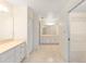 Bright bathroom featuring tile floors, dual sinks and vanities, and an open closet at 2750 Coral Reef Way, Tavares, FL 32778