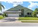 Traditional home with a large driveway, attached garage, and meticulously maintained front lawn at 2750 Coral Reef Way, Tavares, FL 32778