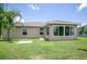 Backyard view of home with the sunroom, palm trees, and lush green lawn at 30 Olive Cir, Ocala, FL 34472
