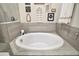 Close-up of modern soaking tub with tiled surround and decorative wall art at 31857 Dahlia Ct, Eustis, FL 32736