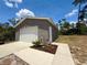 Detached two-car garage with neutral siding and concrete driveway; decorative lawn art to the side of the door at 31857 Dahlia Ct, Eustis, FL 32736