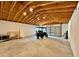 Spacious garage with a high, exposed wood ceiling, concrete floor, and an open roll-up door at 31857 Dahlia Ct, Eustis, FL 32736