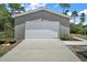 Detached two-car garage with neutral siding and concrete driveway; decorative lawn art to the side of the door at 31857 Dahlia Ct, Eustis, FL 32736