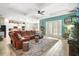 Bright living room with a comfortable leather sofa, a decorative ceiling fan, and ample natural light at 31857 Dahlia Ct, Eustis, FL 32736