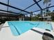 Covered in-ground pool with water jets, surrounded by lush greenery and an outdoor living area at 31857 Dahlia Ct, Eustis, FL 32736