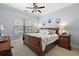 Cozy bedroom featuring a decorative ceiling fan, a comfortable queen bed, and stylish nightstands at 32543 Hawks Lake Ln, Sorrento, FL 32776