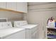 Efficient laundry room with white washer, dryer, and overhead storage space at 3430 Laurel Dr, Mount Dora, FL 32757