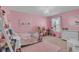 Bedroom with pink walls, pink rug, white trim, and a window providing natural light at 3441 Landing Vw, Tavares, FL 32778