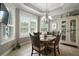 Dining area with large windows, shutter shades, chandelier and a glass table with wicker chairs at 3537 Cluster Ct, The Villages, FL 32163