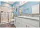 Bathroom features a glass shower, white cabinets, gray countertop, and double sinks at 395 S Dixie Dr, Howey In The Hills, FL 34737