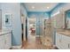 This bathroom features a glass shower, blue walls, double vanity and access to bedroom at 395 S Dixie Dr, Howey In The Hills, FL 34737