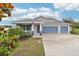 Charming one-story home with a three-car garage, blue accents, and a well-manicured lawn at 395 S Dixie Dr, Howey In The Hills, FL 34737