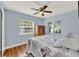 Light-filled bedroom features a ceiling fan, hardwood floors, and two bright windows at 506 Richard St, Leesburg, FL 34748