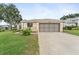 Attached two-car garage with a concrete driveway and neatly trimmed lawn at 5075 China Sea Dr, Tavares, FL 32778