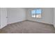 An empty bedroom featuring neutral carpet, white walls, and a large window with a view of the neighborhood at 5105 Blanket Flower St, Apopka, FL 32712