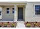 Inviting front entrance featuring a gray door, manicured landscaping, and a cozy porch, perfect for a welcoming first impression at 5105 Blanket Flower St, Apopka, FL 32712