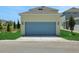 Frontal view of a large blue two-car garage with neutral colored home and well-maintained yard at 5105 Blanket Flower St, Apopka, FL 32712