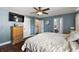Comfortable bedroom with wood floors, a ceiling fan, dresser, and attached bathroom access at 529 Ed Douglas Rd, Groveland, FL 34736