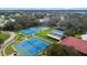 Aerial view of tennis courts, shuffleboard courts, pool and lake in a mature landscape at 5500 Laver St, Leesburg, FL 34748