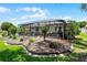 Exterior shot of the screened-in lanai with awning, surrounded by lush landscaping at 5500 Laver St, Leesburg, FL 34748