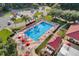 Aerial view of fenced pool, lounge chairs, umbrellas, pool house, trees and parking lot at 5500 Laver St, Leesburg, FL 34748