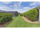 Lush backyard featuring well-kept grass and hedges, leading to a screened-in pool area at 5596 Cedar Waxwing Dr, The Villages, FL 32163