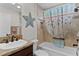 Well-lit bathroom with tiled walls, stylish starfish decoration, and shower with curtain at 5596 Cedar Waxwing Dr, The Villages, FL 32163