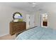 Bedroom featuring wooden dresser with mirror, ceiling fan and view into ensuite bath at 5596 Cedar Waxwing Dr, The Villages, FL 32163