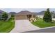 Inviting single-level home showcasing a spacious driveway and a neatly landscaped front yard for a welcoming appeal at 5596 Cedar Waxwing Dr, The Villages, FL 32163