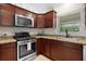 Kitchen featuring stainless steel appliances, dark wood cabinets, and a window view at 5596 Cedar Waxwing Dr, The Villages, FL 32163