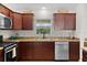 A view of the kitchen featuring stainless steel dishwasher and oven plus wood cabinets at 5596 Cedar Waxwing Dr, The Villages, FL 32163