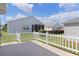 Backyard view featuring a white picket fence, concrete patio, and lush green grass at 744 Shelton St, The Villages, FL 32163