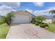Home features a compass rose driveway, attached garage, and lush tropical landscaping at 744 Shelton St, The Villages, FL 32163