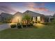 Inviting home with manicured lawn, landscape lighting, and palm trees, captured at dusk at 744 Shelton St, The Villages, FL 32163
