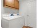 Bright laundry room featuring a washer, dryer, and upper wooden cabinets at 744 Shelton St, The Villages, FL 32163