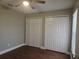 Bedroom featuring two closets, a ceiling fan, neutral walls, and wood-look floors at 8025 Cardinal Winds Ln, Mascotte, FL 34753