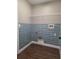 Functional laundry room showcases blue tiled walls, a wire shelf, and wood-look flooring at 8025 Cardinal Winds Ln, Mascotte, FL 34753