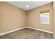 Empty bedroom showcasing wood-look tile flooring, neutral colored walls and trim, with a window to the outside at 8664 Bridgeport Bay Cir, Mount Dora, FL 32757