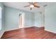 Bedroom with wood flooring, ceiling fan, and a doorway to an en-suite bathroom at 8709 Augusta Ct, Clermont, FL 34711