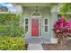 Red front door with decorative plants, tiled floor and sidelight windows, covered porch at 8709 Augusta Ct, Clermont, FL 34711