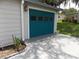 Attached single-car garage with teal door and modern concrete driveway at 941 Tarrson Blvd, Lady Lake, FL 32159