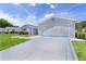 Driveway view showcasing a two-car garage and the well manicured lawn at 9461 Se 173Rd Ln, Summerfield, FL 34491