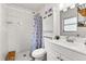 White bathroom featuring tiled shower, updated vanity, and modern fixtures at 9752 County Road 121, Wildwood, FL 34785