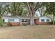 Inviting single story home with brick facade, bright blue shutters, and mature trees in the front yard at 9752 County Road 121, Wildwood, FL 34785