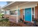 Close up of charming front porch and door featuring brick, blue shutters, and potted plants at 9752 County Road 121, Wildwood, FL 34785