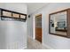 Hallway featuring gray walls, a decorative mirror, storage rack, and a door to the home's exterior at 9752 County Road 121, Wildwood, FL 34785
