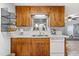 Efficient kitchen with wooden cabinetry, a bright window, and a dishwasher, ideal for cooking and cleaning at 9752 County Road 121, Wildwood, FL 34785