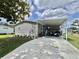 Charming single-story home with gray siding, well-maintained landscaping, and a covered carport perfect for a golf cart at 102 Dogwood Trl, Leesburg, FL 34748