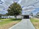 Attractive single-story home with a well-manicured lawn, mature trees, and a convenient covered parking area at 102 Dogwood Trl, Leesburg, FL 34748